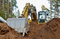 Geotechnical & Risk Assessment Excavator during earthwork for laying Crude oil and Natural gas pipeline in forest area. Installation of gas and crude oil pipes in ground. Construction of the gas pipes to new LNG plant