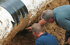 Pipeline Integrity Threat Assessments Two men examining a [pipeline after excavation